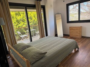 Ein Schlafzimmer mit Bett, Kommode, Spiegel und einem Balkon mit Sitzgelegenheiten.