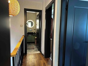 A hallway leading to a bathroom with a mirror, sink, and toilet. - Lavilla Parsdoren House (Karaburun)