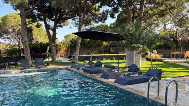 Una piscina con agua cristalina, rodeada de sillas de descanso y sombrillas.
