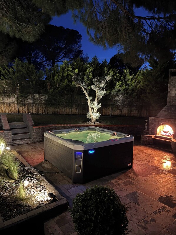 A hot tub with a stone surround, a fire feature, and a wooden deck. - Lavilla Parsdoren House (Karaburun)