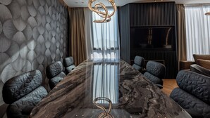 A modern conference room with a marble table, black upholstered chairs, a unique woven light fixture, and a large window with curtains. - Cube (Bar)