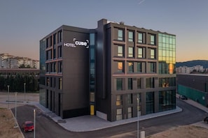 A modern hotel with a prominent 'CUBE' sign, featuring a glass facade and a corner entrance.