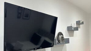 A flat-screen TV mounted on a wall with a minimalist shelf design below it. - The Tower Bridge Hidden Gem (London)