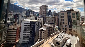A cityscape with modern buildings, a clear sky, and a distant mountain range. - Vista hermosa la carolina 14th floor (Quito)