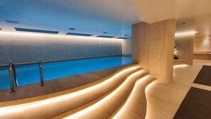 A modern indoor pool area with a curved seating area and a view of the pool. - Vista hermosa la carolina 14th floor (Quito)