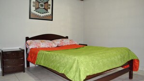 A bedroom with a bed, a nightstand, and a wall decoration. - HOTEL DEL PUENTE BOGOTA (Bogotá)