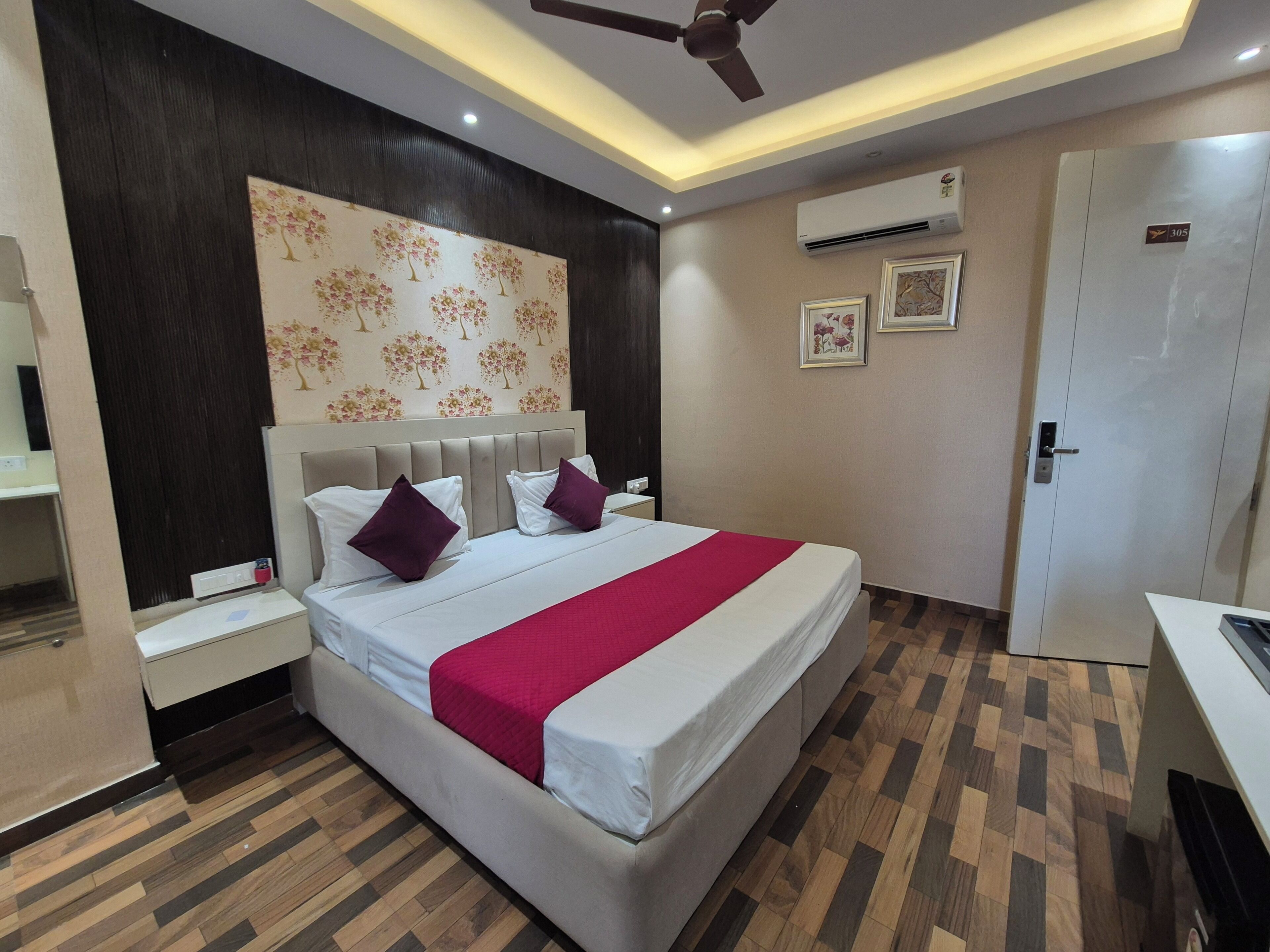A bedroom with a bed, nightstands, a ceiling fan, an air conditioning unit, and a door.