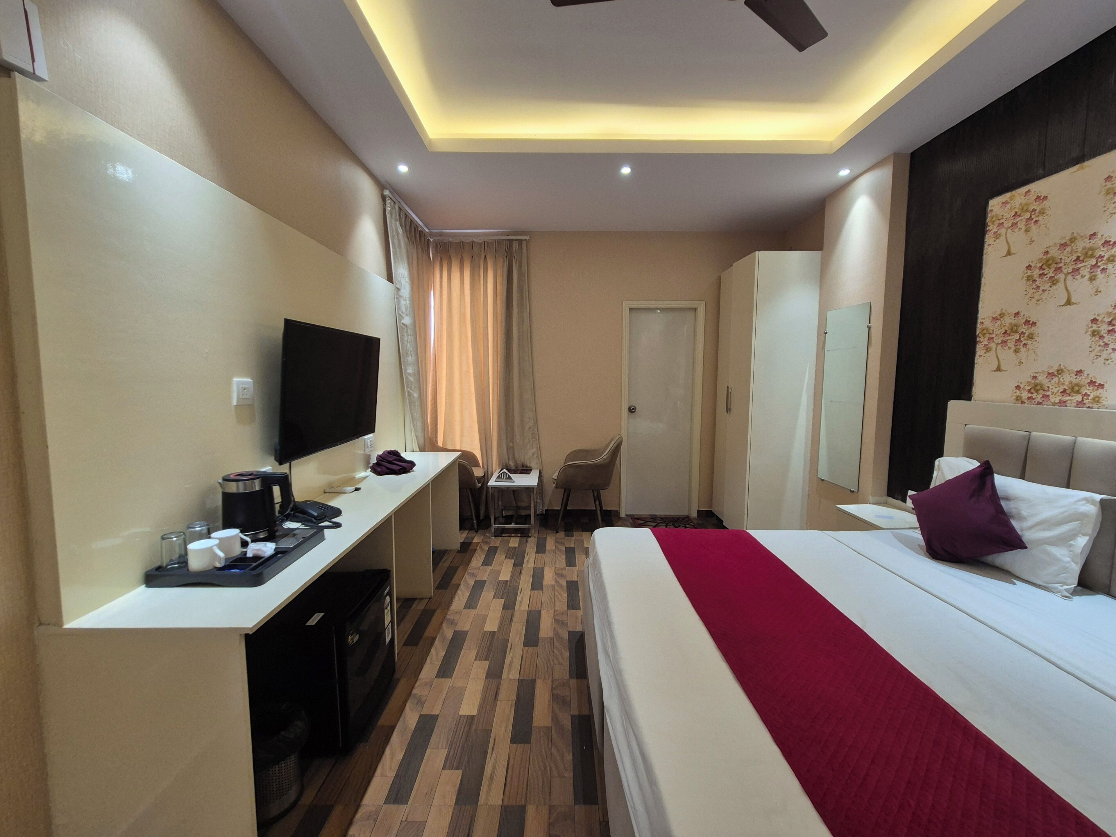 A hotel room with a bed, desk, TV, and a wardrobe.