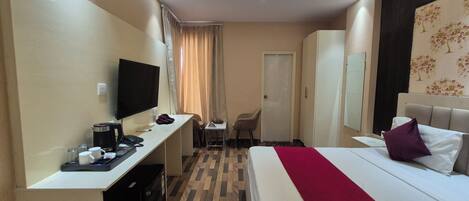 A hotel room with a bed, desk, TV, and a wardrobe.