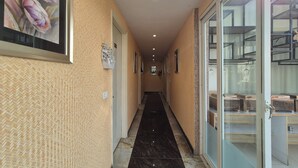 Ein Flur mit Wandmustern, gerahmten Bildern und einer Glastür zu einem Raum mit Regalen.
