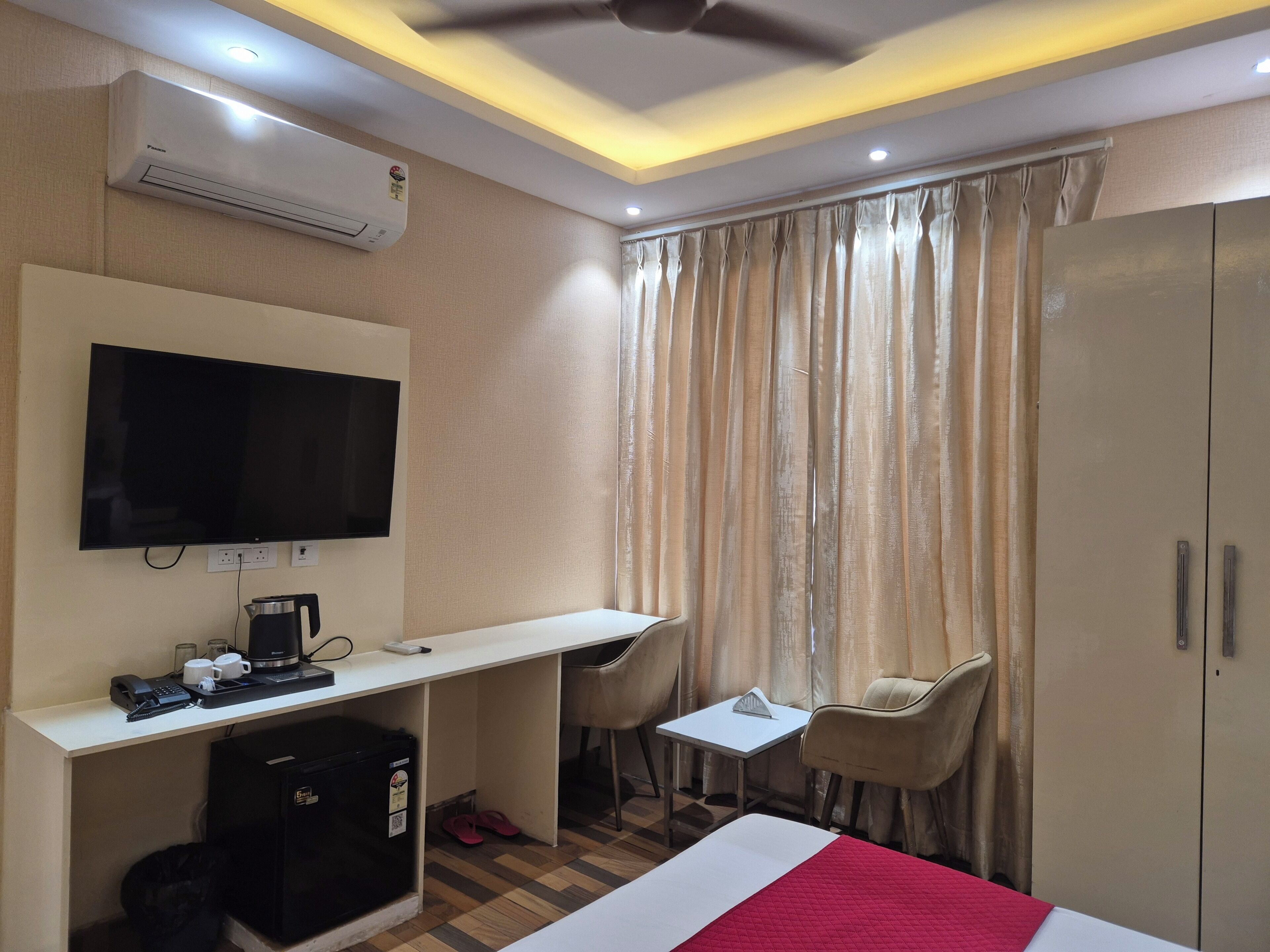 Habitación de hotel con cama, escritorio con televisor, armario, mesita y silla.