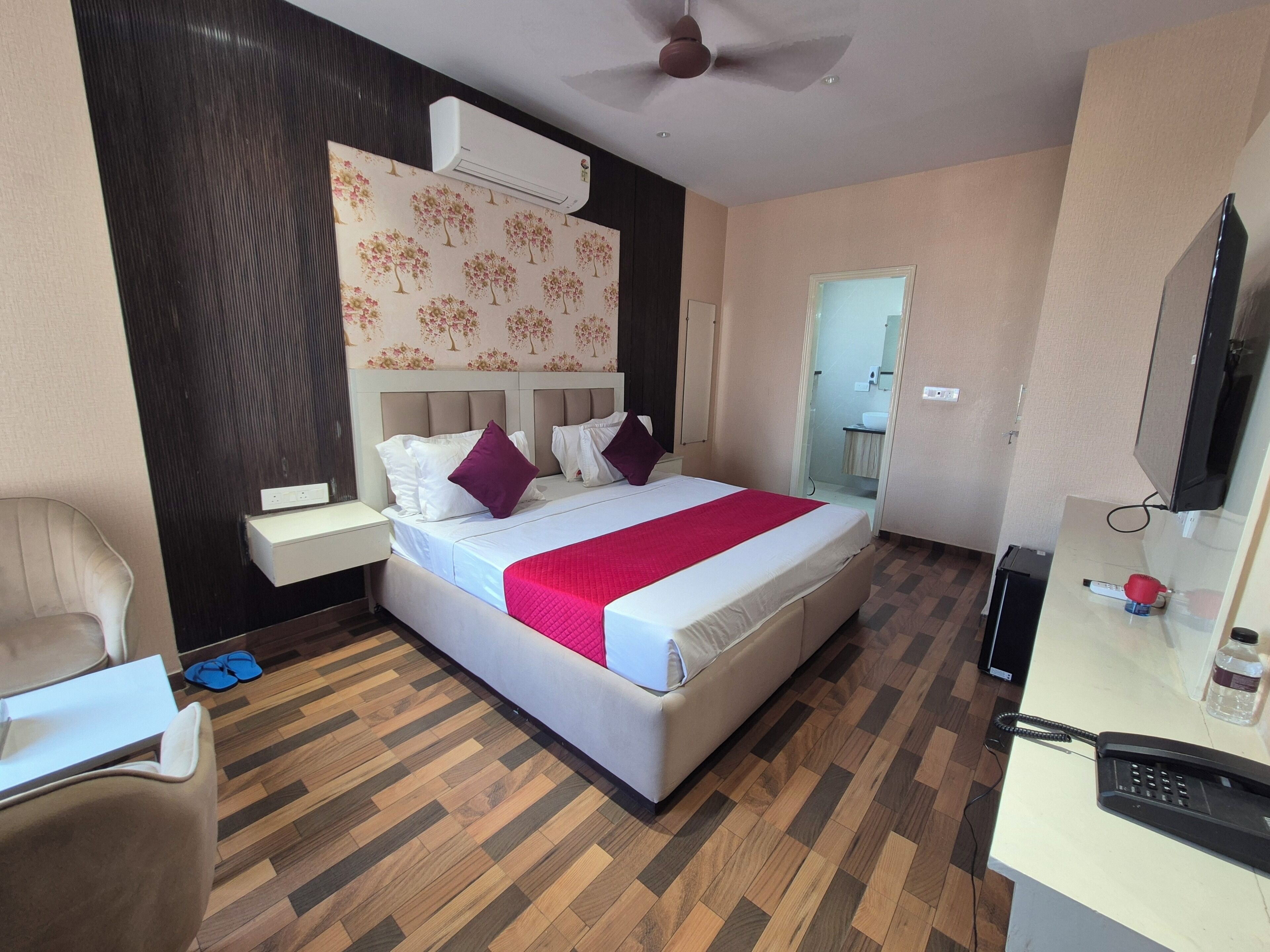 A hotel room with a bed, bedside table, chair, and a desk with a telephone.