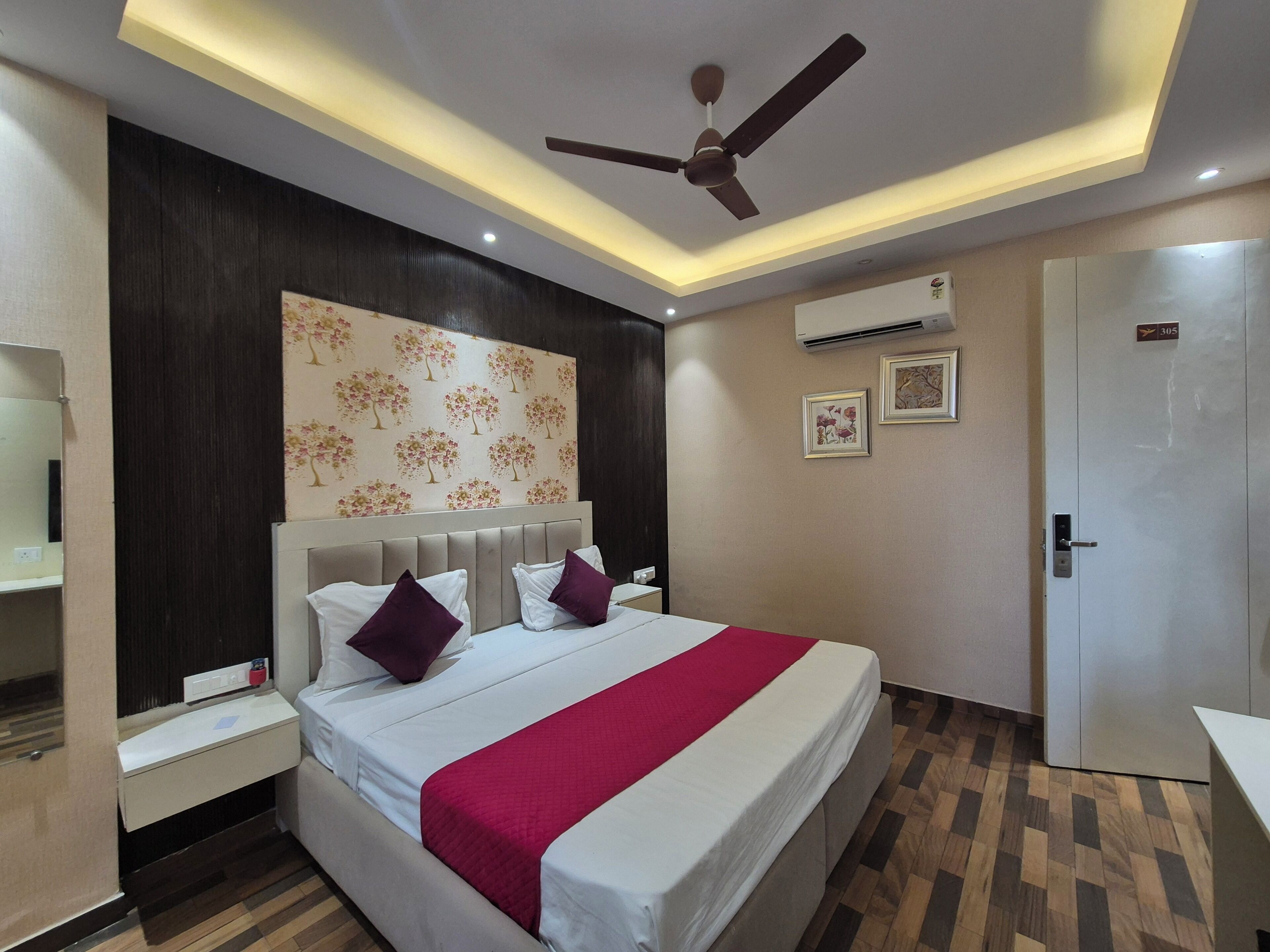 A hotel room with a bed, nightstands, a ceiling fan, an air conditioning unit, and a door.