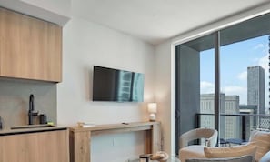 Eine moderne Küche mit Flachbildfernseher, einem Essbereich mit Tisch und Stühlen sowie ein Balkon mit Blick auf die Stadt.