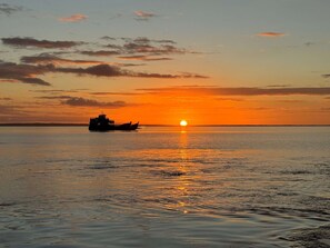 A sunset over a calm body of water with a boat in the foreground. - 719 Cooloola Villa Kingfisher Bay K Gari Fraser Island (K'gari (Fraser Island))