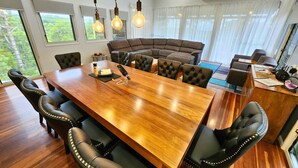 Un coin repas avec une table en bois, des chaises à revêtement noir, un canapé marron et un ventilateur de plafond.