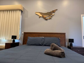 A hotel room with a large bed, two pillows, a wooden headboard, a wall-mounted artwork, a bedside table with a lamp, and a window with blinds. - Bushy s Hilltop Kingfisher Bay K Gari Fraser Island (K'gari (Fraser Island))