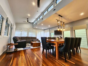A modern living room with a sofa, dining table, chairs, and a ceiling fan. - Bushy s Hilltop Kingfisher Bay K Gari Fraser Island (K'gari (Fraser Island))