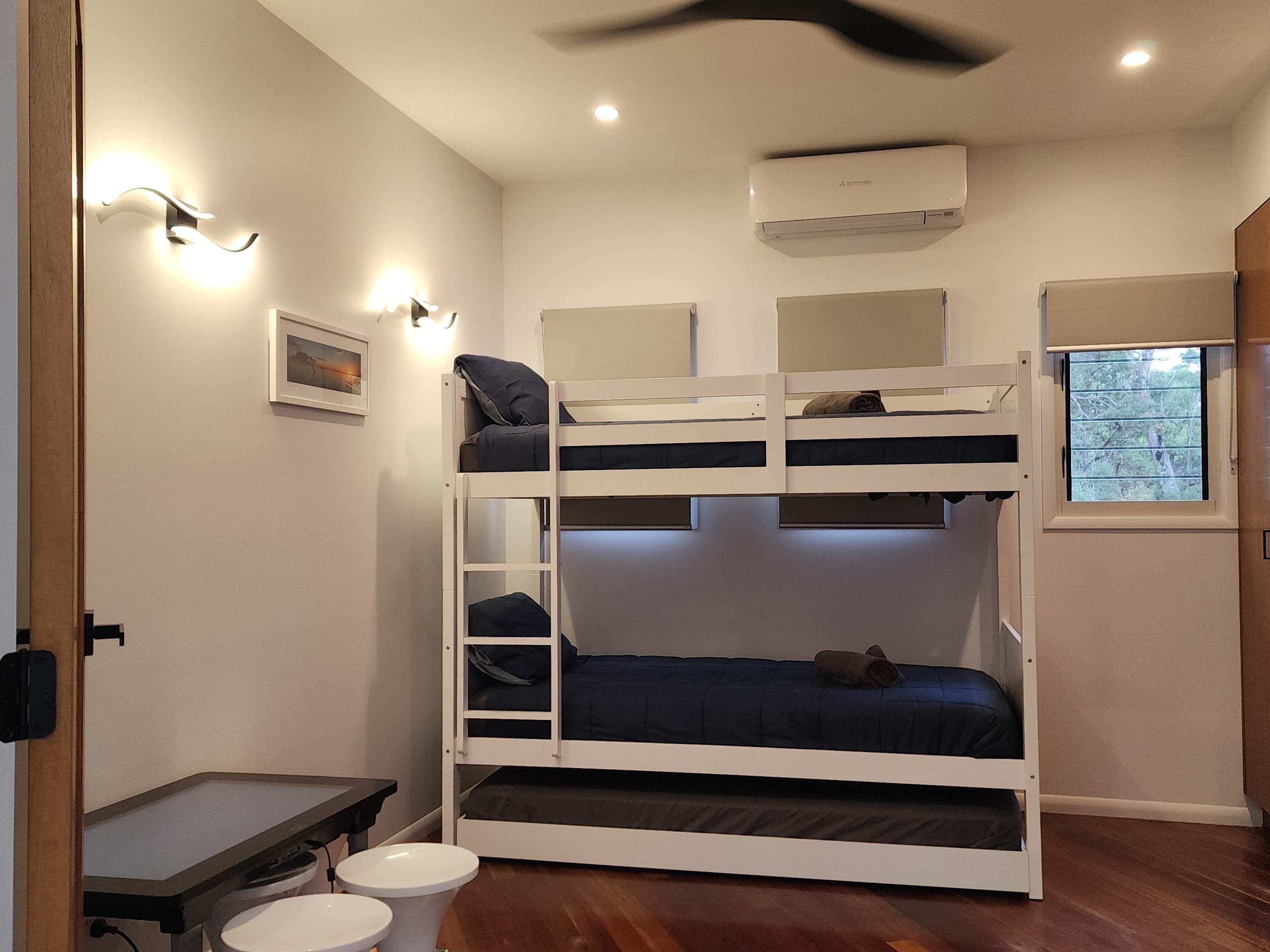 Habitación con literas, un escritorio, una ventana y aire acondicionado.