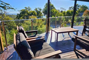 A deck with wooden furniture, including chairs and a table, overlooking a forested area. - Bushy s Hilltop Kingfisher Bay K Gari Fraser Island (K'gari (Fraser Island))