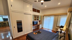 Une chambre à coucher avec un lit, un bureau, une chaise, une télévision et une fenêtre avec des rideaux.
