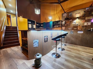 A bar area with a wooden bar counter, stools, and various license plates on the wall.