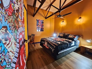 A bedroom with a bed, a ceiling fan, a wall with a poster, and a window.