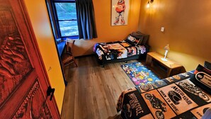 Une chambre à coucher avec un lit, un bureau, une chaise, une fenêtre et un ventilateur de plafond.