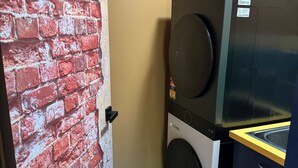 Une buanderie avec un mur en briques, un lave-linge et un sèche-linge placés l’un sur l’autre.