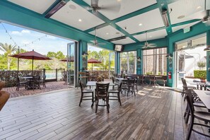 Eine Außenpatio-Terrasse mit Holzboden, Tischen, Stühlen und Sonnenschirmen.