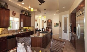 A modern kitchen with dark wood cabinets, a stainless steel refrigerator, and a central island with a stove. - Spacious 4-bedroom house with Golf Course view in marvelous Bermuda Dunes. (Bermuda Dunes)