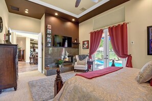 A bedroom with a bed, a fireplace, a TV, and a view of a swimming pool. - Spacious 4-bedroom house with Golf Course view in marvelous Bermuda Dunes. (Bermuda Dunes)