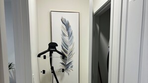 Käytävä, jossa on lattialla imuri, seinällä kehystetty taideteos ja ovi.