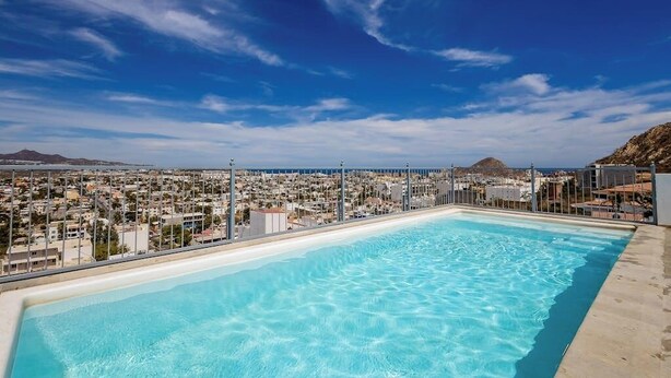 A rooftop pool with a city view, surrounded by a fence. - Hotel Suite With Ocean-view Rooftop Infinity Pool, Balconies & AC (Cabo San Lucas)