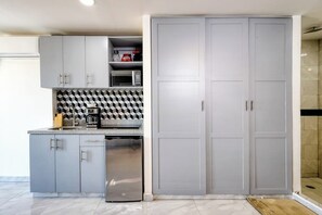 A modern kitchen with grey cabinets, a microwave, and a coffee maker. - Hotel Suite With Ocean-view Rooftop Infinity Pool, Balconies & AC (Cabo San Lucas)