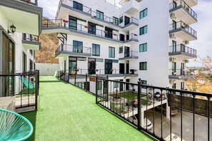 A multi-story residential building with balconies, a green artificial lawn, and a view of the surrounding area. - Hotel Suite With Ocean-view Rooftop Infinity Pool, Balconies & AC (Cabo San Lucas)
