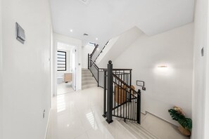 Een modern interieur met een trap, een hal en een deur naar de badkamer.
