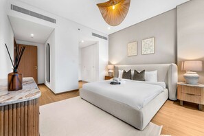 Ein modernes Schlafzimmer mit einem großen Bett, Nachttischen, einem Holztisch und einer Pendelleuchte.