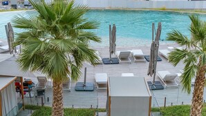 A poolside area with lounge chairs, umbrellas, and palm trees. - Free Housekeeping Visits During Your Stay - Stayshort - Bright 2 Bedroom in Madinat Jumeirah Living That Sleeps 6 With Balcony (Dubai)