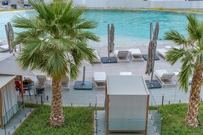 Ein Poolbereich mit Liegestühlen, Sonnenschirmen und Palmen.