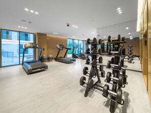 Ein modernes Fitnessstudio mit Laufbändern, Crosstrainern und Gewichten.