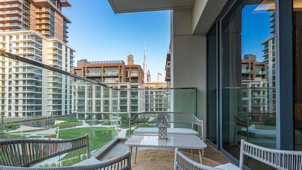A balcony with wicker furniture, a glass railing, and a view of high-rise buildings. - Free Housekeeping Visits During Your Stay - Stayshort - Bright 2 Bedroom in Madinat Jumeirah Living That Sleeps 6 With Balcony (Dubai)
