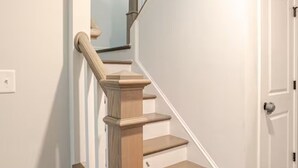 Una scala con gradini in legno e un corrimano, che conduce a una porta.