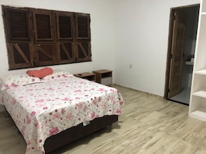 A bedroom with a bed, a wooden headboard, a small bedside table, and a wardrobe.