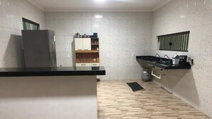 Een keuken met een koelkast, houten kastjes, een aanrecht en een spoelbak.