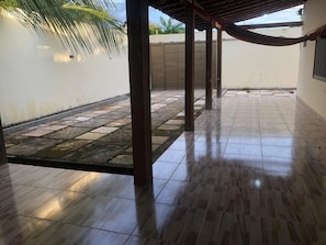 A covered outdoor area with tiled flooring, a palm tree, and a closed gate.