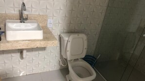 Een badkamer met een witte wastafel, toilet en douchehoek.