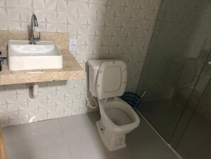 Un baño con lavamanos blanco, inodoro y zona de ducha.