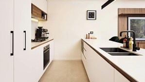 A modern kitchen with white cabinetry, a built-in oven, a coffee machine, and a large window with a forest view. - The Brass Banana in Petersham (Sydney)