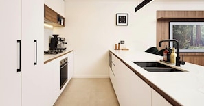 A modern kitchen with white cabinetry, a built-in oven, a coffee machine, and a large window with a forest view. - The Brass Banana in Petersham (Sydney)